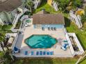 Aerial view showcases a sparkling community pool with lounge chairs and a jacuzzi surrounded by lush landscaping at 8704 Knightsbridge Ct # B, Kissimmee, FL 34747