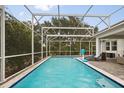 A screened in pool with lounge chairs and view of trees at 8811 Bally Neal Loop, Davenport, FL 33896