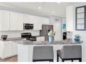 Well-lit kitchen featuring white cabinetry, stainless steel appliances, and a stylish breakfast bar with counter seating at 987 Nathan Ridge Rd, Clermont, FL 34715