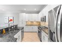 This modern kitchen features stainless steel appliances, granite countertops, and ample white cabinet storage at 10430 Belfry Cir, Orlando, FL 32832
