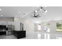 Open-concept living space with a black kitchen island, ceiling fan, stainless steel appliances, and modern lighting at 13619 Sw 78Th Place, Dunnellon, FL 34432