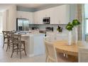 Bright kitchen featuring white cabinets, stainless steel appliances, an island, and an adjacent dining area at 152 Fredericksburg Ave, Orange City, FL 32763