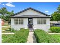 Charming white stucco bungalow featuring black trim, symmetrical windows, and manicured front hedges at 161 Bolender Rd, Auburndale, FL 33823