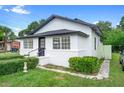 Angled view of the charming white home with black trim, complemented by lush landscaping and a well-maintained lawn at 161 Bolender Rd, Auburndale, FL 33823