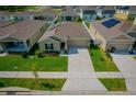 Aerial view of a well-kept home with a two-car garage, solar panels and a pristine lawn in a residential neighborhood at 214 Brave Rd, Davenport, FL 33837
