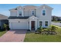 Inviting two-story home with a well-manicured lawn, beautiful landscaping, paver driveway, and attached garage at 3077 Nottel Dr, St Cloud, FL 34772