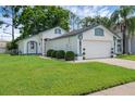 Charming single-story home features a two-car garage, landscaped yard, and freshly painted white and blue exterior at 5729 Norman H Cutson Dr, Orlando, FL 32821