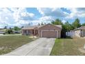 Inviting single-story home with a well-manicured lawn, a concrete driveway, and charming curb appeal on a sunny day at 7135 Sw 129Th St, Ocala, FL 34473