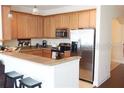 Well-equipped kitchen with stainless steel appliances, light wood cabinets, and a breakfast bar at 7842 Holiday Isle Dr # 102, Belle Isle, FL 32812