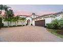 An elegant front exterior view of a property showcasing the well-manicured brick drive and palm trees at 9743 Covent Garden Dr, Orlando, FL 32827