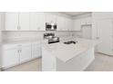 Bright kitchen featuring a central island, white cabinets, and stainless steel appliances at 150 Fredericksburg Ave, Orange City, FL 32763