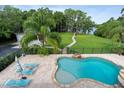 Aerial view of a backyard oasis featuring a stone-lined pool, spa, and lush tropical landscaping at 1550 Bluewater Run, Chuluota, FL 32766