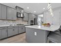 Close-up of a gray kitchen featuring a spacious island, stainless steel appliances, and stylish backsplash at 2845 High Pointe St, Clermont, FL 34711
