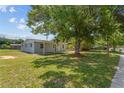 Spacious, sunny yard with mature trees and a view of the home's front exterior, showcasing its curb appeal at 7701 Cassino Ave, Orlando, FL 32819