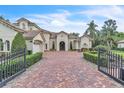 Charming home with a brick driveway, manicured landscaping, wrought iron gates, and a three-car garage at 9729 Lake Hugh Dr, Gotha, FL 34734
