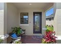 Front porch of home with decorative front door, red brick pavers, seating, and colorful landscaping at 1392 Lombardi Ct, Kissimmee, FL 34759