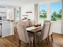 Bright dining area with hardwood floors, a wooden table, and expansive windows overlooking a lush landscape at 2782 Virginia Pine Dr, Bartow, FL 33830