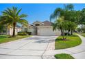 Beautiful single-story home with a manicured lawn, paver driveway and lush palm trees at 2830 Alton Dr, Kissimmee, FL 34741