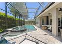 Inviting screened-in pool area with a spa, brick patio, and comfortable outdoor seating at 390 Anessa Rose Loop, Ocoee, FL 34761
