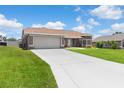 View of home showcasing its well-kept lawn, long driveway, and attached two-car garage at 801 Hunt Dr, Lake Wales, FL 33853