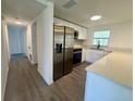 Modern kitchen featuring stainless steel appliances, white cabinets, and an adjacent hallway at 804 Starke Lake Cir, Ocoee, FL 34761