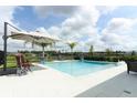 A luxurious backyard pool featuring modern tiling, outdoor seating, and an umbrella at 1313 Middle Lake Dr, Ormond Beach, FL 32174