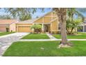 Single-Gathering home featuring a well-manicured lawn, lush landscaping, and two-car garage on a sunny day at 14312 Paradise Tree Dr, Orlando, FL 32828