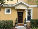 Welcoming front door with elegant wreath, decorative potted plants, and manicured hedges at 14344 Desert Haven St, Windermere, FL 34786