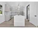 Modern kitchen featuring an oversized island, stylish light fixtures, and stainless steel appliances at 17657 Windy Pine St, Montverde, FL 34756