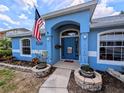 Welcoming entrance with American flag, decorative plants, and blue painted facade at 2963 Beckwith St, Deltona, FL 32738