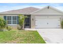 Close up of charming single-story home featuring a neutral paint scheme and a two-car garage with a well manicured lawn at 341 Alexzander Way, Winter Haven, FL 33881
