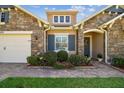 Charming home showcasing stone accents, blue shutters, and a well-manicured lawn with flower beds at 4133 Foxhound Dr, Clermont, FL 34711