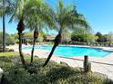Community pool surrounded by tropical palm trees and shrubbery at 6451 Old Park Ln # 407, Orlando, FL 32835