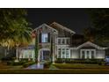 Night shot of a beautiful home featuring a stone facade, manicured landscaping, and a brick walkway at 7550 John Hancock Dr, Winter Garden, FL 34787