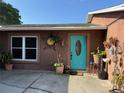 Close up of the turquoise front door surrounded by potted plants and a concrete entryway with decorative accents at 11314 Huggins St, Leesburg, FL 34788