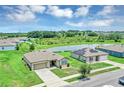 Aerial view of home with a pond view, landscaped yard, and houses with solar panels on the roofs at 16406 Blooming Cherry Dr, Groveland, FL 34736
