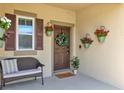 Inviting front porch with a cozy bench, decorative plants, and a welcoming door at 16406 Blooming Cherry Dr, Groveland, FL 34736