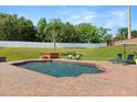 Backyard pool area with brick pavers, hot tub, lounge chairs, and umbrella, surrounded by lush greenery at 4065 Shadowind Way, Gotha, FL 34734