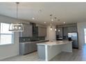 Open-concept kitchen with gray cabinets, stainless steel appliances, and an oversized kitchen island at 605 Big Pine Ave, Minneola, FL 34715