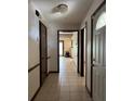 Hallway with tiled floor, bright chandelier, and multiple doors, showcasing access to various rooms at 6616 Blanche Ct, Orlando, FL 32818