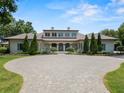 A stately home featuring a circular driveway, manicured landscaping, and symmetrical design elements at 1112 Preserve Point Dr, Winter Park, FL 32789