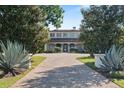 View of an elegant home, framed by mature trees, with a large circular driveway and landscaped entrance at 1112 Preserve Point Dr, Winter Park, FL 32789