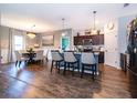 Open-concept kitchen with granite island, dark cabinetry, modern appliances, and pendant lighting adjacent to dining space at 16379 Blooming Cherry Dr, Groveland, FL 34736