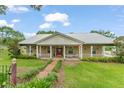 Charming home featuring a metal roof, inviting front porch, and meticulously landscaped yard at 17523 Doris St, Montverde, FL 34756