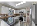 Functional kitchen featuring granite countertops, white cabinetry, stainless steel appliances, and wood-look flooring at 202 Ferryboat Ct, Orlando, FL 32828