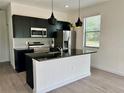 Modern kitchen featuring stainless steel appliances, dark cabinets and island with seating at 3301 Tranquil Trl, Kissimmee, FL 34747