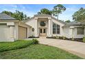 Beautiful home exterior features an attached garage, well-manicured lawn, double doors, and architectural pillars at 388 Hampton Hills Ct, Debary, FL 32713