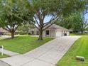 Exterior view of the home with large trees, a side-entry garage, and a long driveway at 11648 Grand Bay Blvd, Clermont, FL 34711
