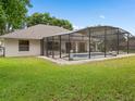 Back exterior view of a screened in pool with neutral paint and well maintained yard at 11648 Grand Bay Blvd, Clermont, FL 34711