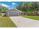 The lovely gray home features an extra long driveway, well maintained lawn, and mature trees at 122 Seville Rd, Auburndale, FL 33823